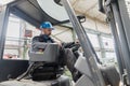 Happy mature man fork lift truck driver lifting pallet in storage warehouse . Royalty Free Stock Photo