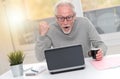 Happy mature man having a good surprise on laptop, light effect Royalty Free Stock Photo