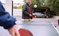 Happy mature man and his son playing table tennis outdoor during quarentine because of COVID 19, coronavirus