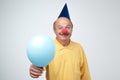 Happy mature man with red clown nose and blue ballon on birthday party. Royalty Free Stock Photo