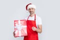 happy mature man in santa hat and red apron hold present. pointing finger Royalty Free Stock Photo