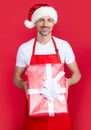 happy mature man in santa hat and red apron holding present Royalty Free Stock Photo