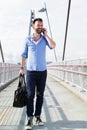 Happy mature man walking on bridge and using mobile phone Royalty Free Stock Photo