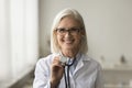 Happy mature medical practitioner using stethoscope head shot portrait