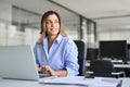 Happy middle aged business woman using laptop looking away in office. Royalty Free Stock Photo