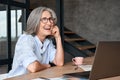 Happy mature middle aged woman laughing sitting at workplace with laptop. Royalty Free Stock Photo