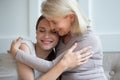 Happy mature mom hug grownup daughter relaxing at home together
