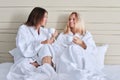Happy mature mother and teenage daughter drinking coffee, talking, smiling Royalty Free Stock Photo