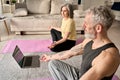 Happy mature old couple doing yoga meditating together at home with laptop. Royalty Free Stock Photo