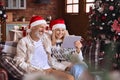 Happy mature old couple using digital tablet relaxing on couch on Christmas. Royalty Free Stock Photo