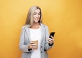 Happy mature old 60s woman with long hair holding smartphone and takeaway coffee Royalty Free Stock Photo