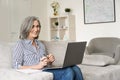 Happy mature mid age woman working on laptop computer from home office. Royalty Free Stock Photo