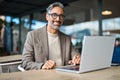 Happy mature business man executive sitting at outdoor table using laptop. Royalty Free Stock Photo