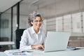 Happy mature professional business woman working on laptop computer in office. Royalty Free Stock Photo