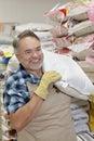 Happy mature salesperson carrying sack in feed store