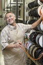 Happy mature salesperson standing by electrical wire spool while looking away in hardware store