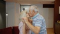 Happy mature senior couple dancing laughing in kitchen at home, celebrating anniversary, having fun Royalty Free Stock Photo