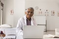 Happy mature senior Indian doctor man sitting at clinic workplace Royalty Free Stock Photo