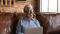 Happy mature senior 70s man using laptop, sitting on sofa Royalty Free Stock Photo
