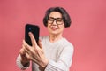 Happy mature senior woman holding smartphone using mobile online apps, smiling old middle aged grandmother texting sms message Royalty Free Stock Photo