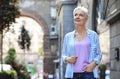 Happy mature woman on city street, space for text Royalty Free Stock Photo