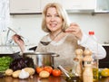 Happy mature woman cooking soup