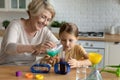 Happy mature woman with curious little girl making funny experiments