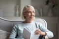 Happy mature woman distracted from reading book at home Royalty Free Stock Photo