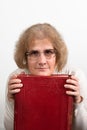 Happy mature woman with glasses holding old red paperback book Bible Royalty Free Stock Photo