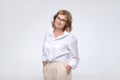 Happy mature woman in glasses and white shirt standing on a white background. Royalty Free Stock Photo