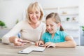 Happy mature woman and granddaughter solving jigsaw puzzle Royalty Free Stock Photo