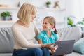 Happy mature woman and granddaughter using laptop in living room Royalty Free Stock Photo