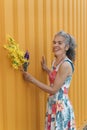 Laughing mature woman with flowers Yellow background Royalty Free Stock Photo