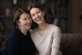 Happy mature woman with grownup daughter hugging sitting on couch Royalty Free Stock Photo