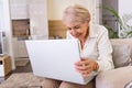 Happy mature woman having a video call over laptop at home. Gray-haired senior woman waving hand in front of laptop while having Royalty Free Stock Photo