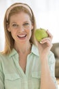 Happy Mature Woman Holding Granny Smith Apple At Home Royalty Free Stock Photo