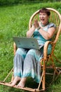 Happy mature woman with laptop in rocking chair
