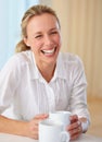 Happy mature woman, laughing and coffee for funny joke, conversation or humor on kitchen table at home. Blonde female