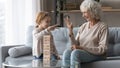 Happy mature woman and little granddaughter playing board game