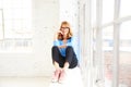 Happy mature woman looking at camera and smiling while relaxing at the window Royalty Free Stock Photo