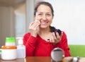 Happy mature woman puts facepowder