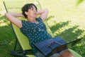 Happy mature woman relaxing resting on the deck chair in garden