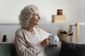 Happy mature woman relaxing on sofa with cup of tea. Royalty Free Stock Photo