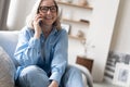 Happy mature woman speaking on smartphone. Senior grey haired lady making telephone call, sitting on couch at home Royalty Free Stock Photo