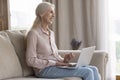 Happy mature woman spend time on internet using laptop