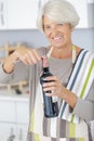 happy mature woman uncorking wine bottle Royalty Free Stock Photo