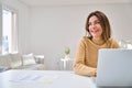 Happy mature woman using laptop at home table looking away at copy space. Royalty Free Stock Photo