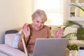 Happy mature woman waving to someone while having a video call over laptop at home. Gray-haired senior woman waving hand in front Royalty Free Stock Photo