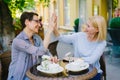 Happy women friends doing high-five and laughing in outdoor cafe in summer