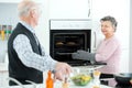 Happy matured woman opening microwave oven at kitchen